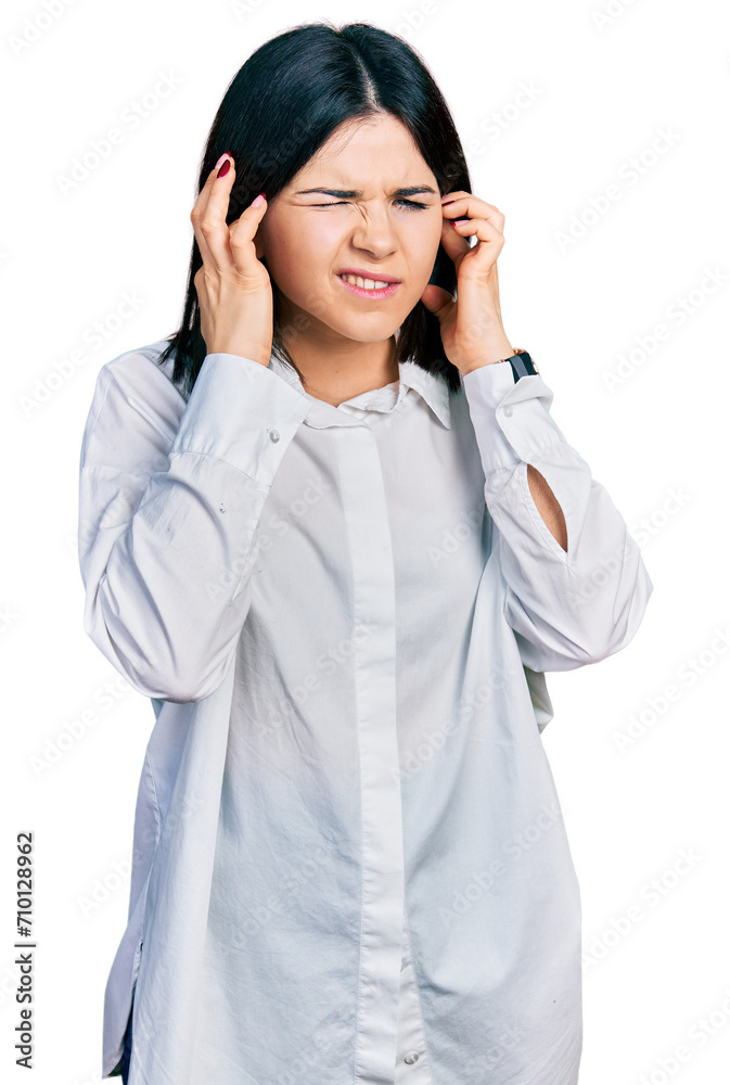 Young brunette woman with blue eyes wearing oversize white shirt covering ears with fingers with annoyed expression for the noise of loud music. deaf concept. Young brunette woman with blue eyes wearing oversize white shirt covering ears with fingers with annoyed expression for the noise of loud music. deaf concept.
