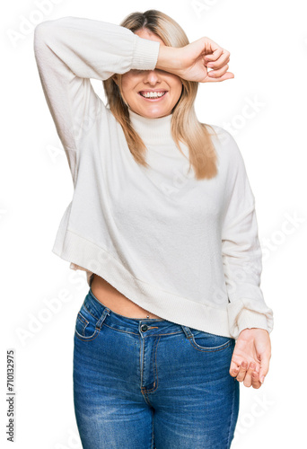 Young caucasian woman wearing casual winter sweater covering eyes with arm smiling cheerful and funny. blind concept.