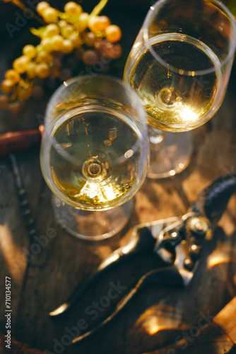 Top view of two glasses of white wine on a barrel with yellow grape and secateurs