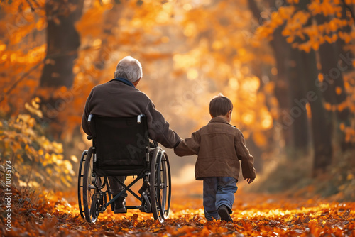 A grandson rides a wheelchair with his grandfather in the fall