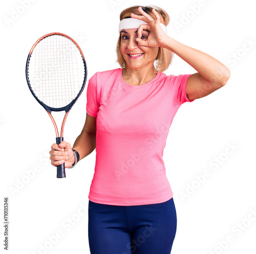 Young blonde woman playing tennis holding racket smiling happy doing ok sign with hand on eye looking through fingers © Krakenimages.com