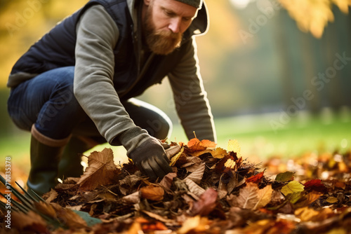 Man is picking up leaves from ground. Ideal for autumn-themed designs and gardening-related projects.