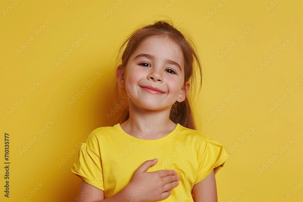 I swear, promise you not regret. Portrait of happy, sincere little girl raising one arm and hold hand on heart as give oath, pledge, telling truth, want you to believe, standing over yellow background I swear, promise you not regret. Portrait of happy, sincere little girl raising one arm and hold hand on heart as give oath, pledge, telling truth, want you to believe, standing over yellow background