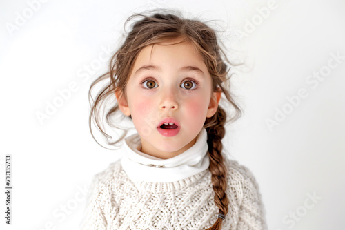 Expressive facial expression. Shocked stupefaction A beautiful little girl in fashionable clothes stands on a white background, with her jaw hanging open, feeling stunned by what she sees around her photo