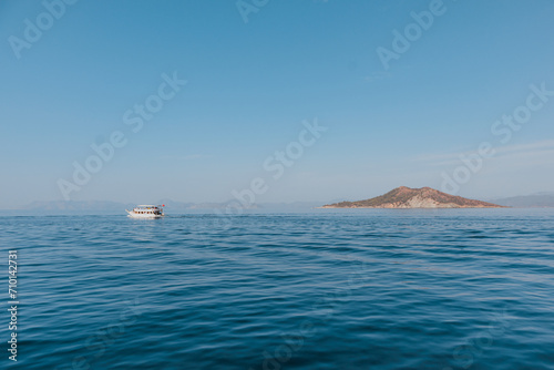 White boat and picturesque island in the sea on the horizon