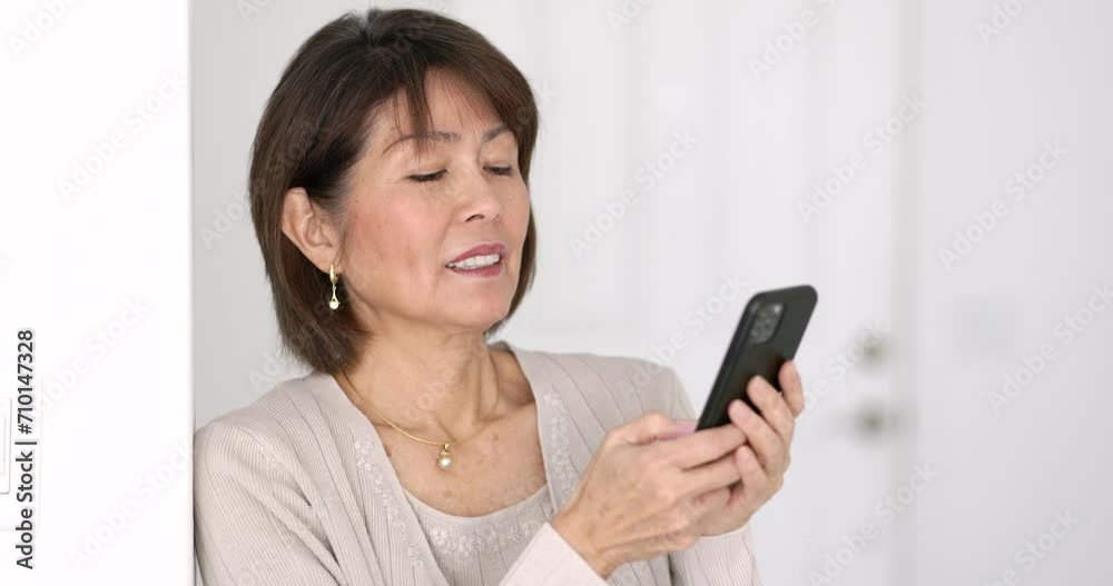 Attractive woman relaxing leaning against white wall smiling enjoying reading texting email on mobile phone bright white background. Attractive woman relaxing leaning against white wall smiling enjoying reading texting email on mobile phone bright white background.