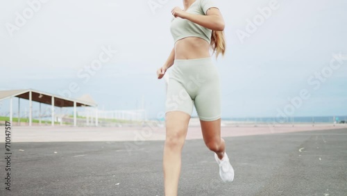 Sportswoman injures knee while running during outdoor training. Young female athlete running on asphalt stops and touches her knee while feeling a sharp pain. Knee sprain. Meniscal injury.  photo