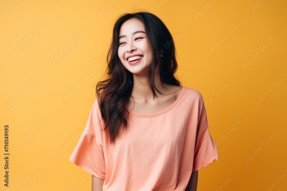 Portrait of a beautiful young asian woman laughing over yellow background Portrait of a beautiful young asian woman laughing over yellow background
