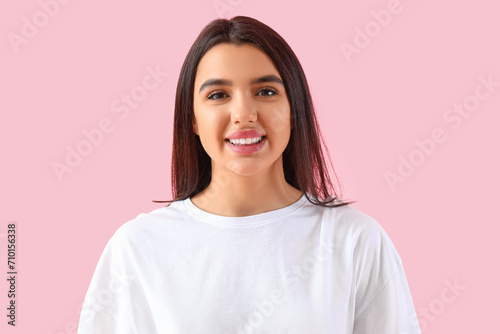 Smiling young woman with healthy teeth on pink background