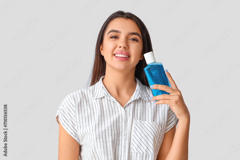 Smiling young woman with mouth rinse on light background Smiling young woman with mouth rinse on light background