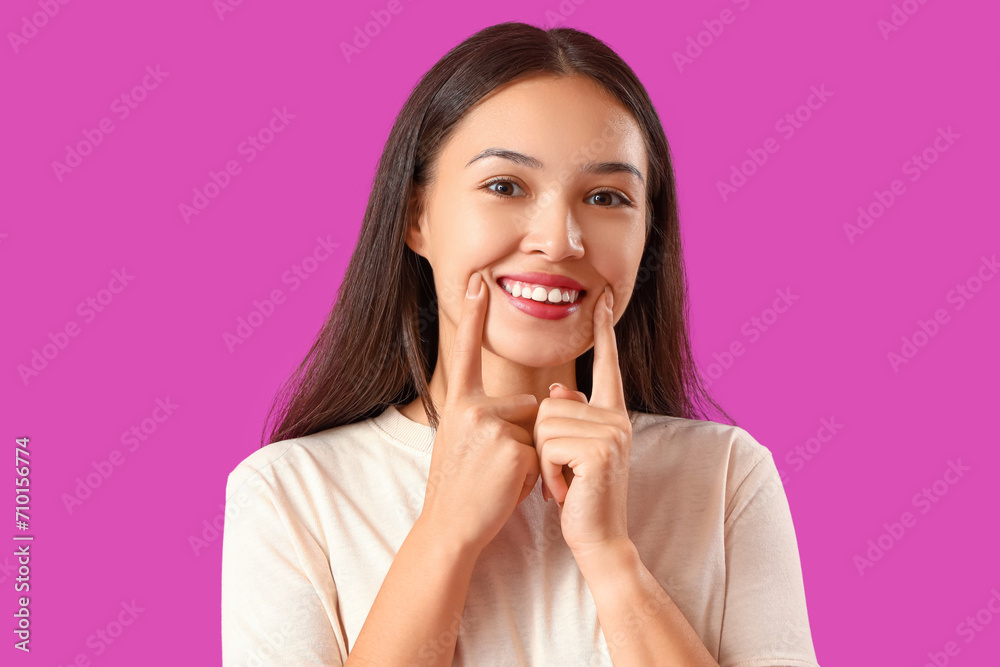 Smiling young Asian woman with healthy teeth on purple background, closeup Smiling young Asian woman with healthy teeth on purple background, closeup
