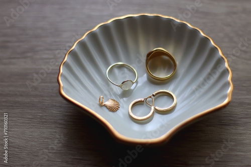 Obraz na płótnie Ring dish shaped like a seashell with gold rings, earrings and pendant. Wooden background, selective focus. w salonie