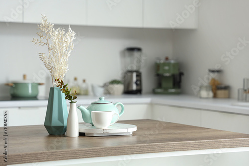 Wooden table with tea set, dried flowers and eucalyptus branches in modern kitchen © Pixel-Shot