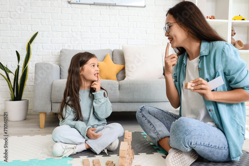 Female Asian speech therapist teaching little girl how to pronounce letter D in office