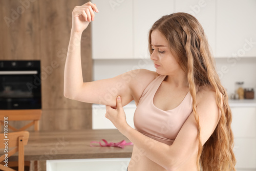 Upset young woman with chubby arms at home. Weight gain concept