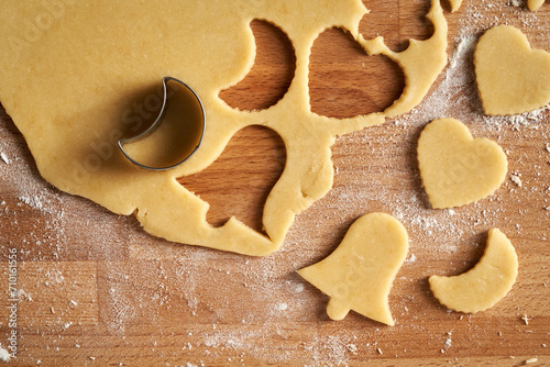 Cutting out star and bell shapes from pastry dough to prepare Linzer Christmas cookies