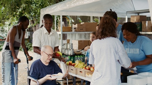 Slika na platnu Charitable team offers help to the destitute and distributes free food including fresh fruits to homeless