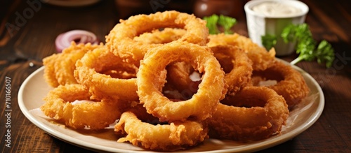 Onion rings, homemade and deep-fried, selectively focused on the plate.