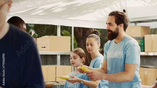 Canvas Print Male and female volunteers share food and provisions with less privileged during charity food drive