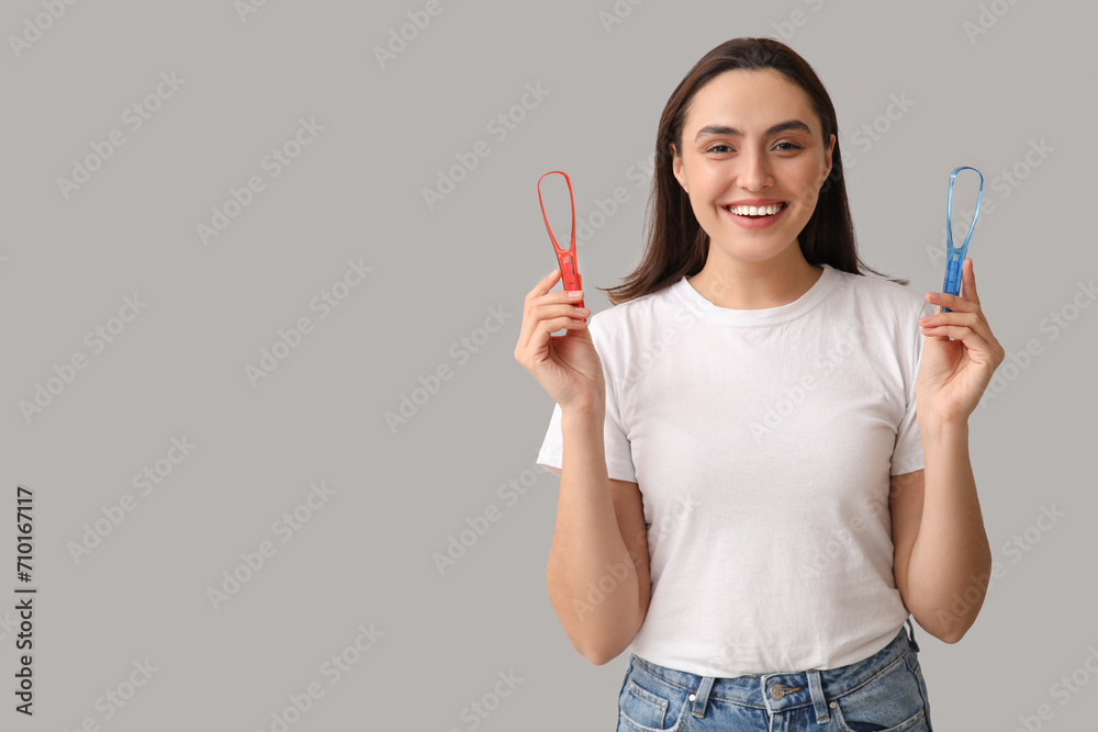 Young woman with tongue scrapers on light background - obrazy, fototapety, plakaty 
