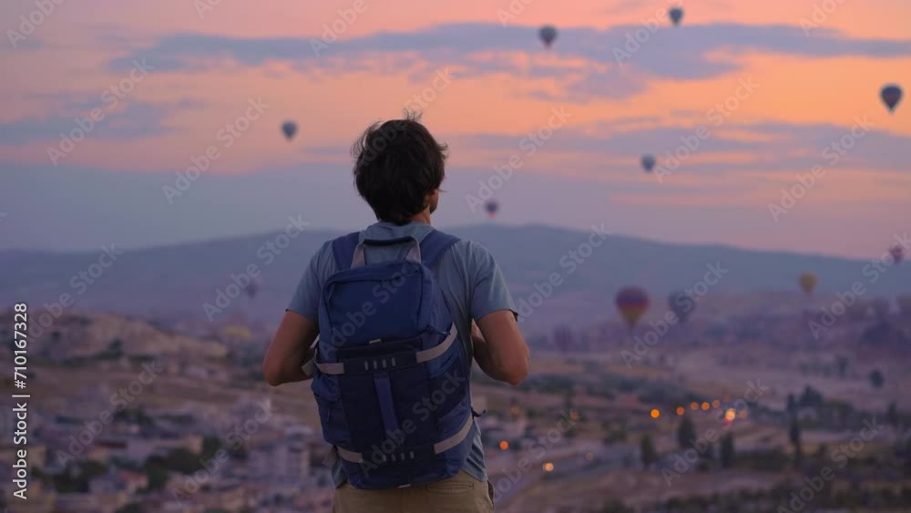 A young man tourist is looking at hot air balloons in Cappadocia, Turkey. Happy Travel in Turkey. A young man tourist is looking at hot air balloons in Cappadocia, Turkey. Happy Travel in Turkey.
