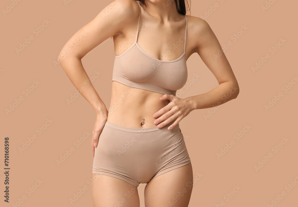 Beautiful young woman in nude underwear on beige background