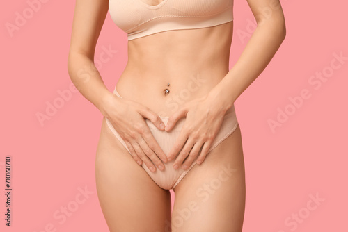 Beautiful young woman in underwear on pink background