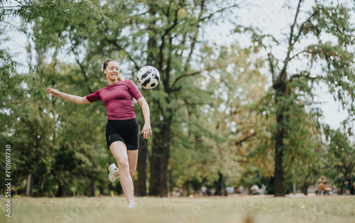 Gorgeous, female, football player kicking a football in the air. Copy space.