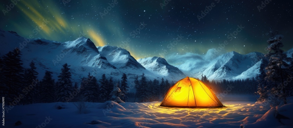 Winter field with a yellow tent illuminated from within, surrounded by a breathtaking starry sky and the Northern lights. Spectacular nocturnal scene. - obrazy, fototapety, plakaty 
