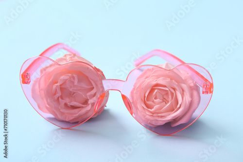 Pink heart shaped sunglasses with roses on blue background. Valentine's Day concept