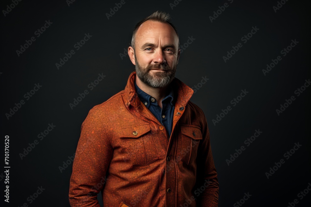 Portrait of a stylish bearded man in a jacket on a dark background.