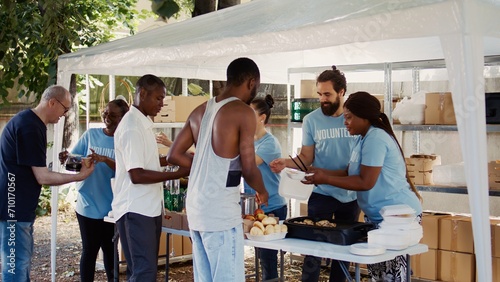 Male and female volunteers distribute prepared meals to homeless people and provide humanitarian aid. This scenario shows the significance of community solidarity and helping those in need. photo