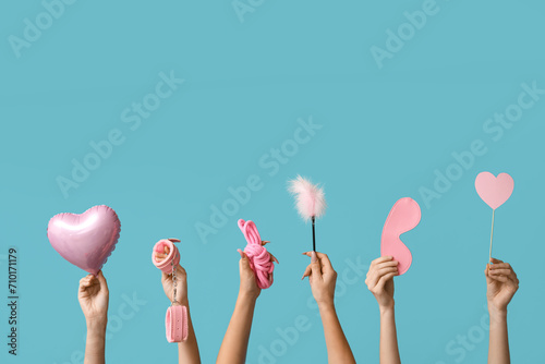 Many female hands with heart shaped balloon and sex toys on blue background. Valentine's Day celebration photo
