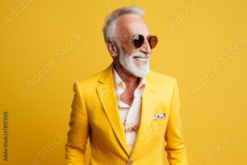 portrait of senior man in sunglasses and yellow jacket on yellow background photo