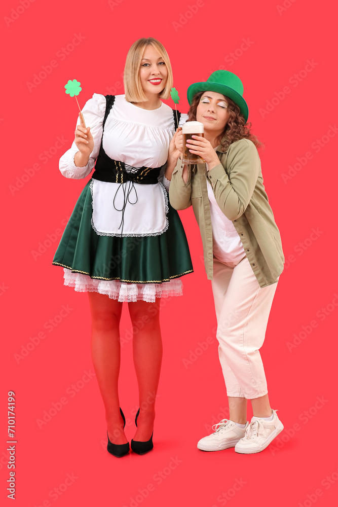 Fototapeta premium Portrait of women with beer celebrating St. Patrick's Day on red background