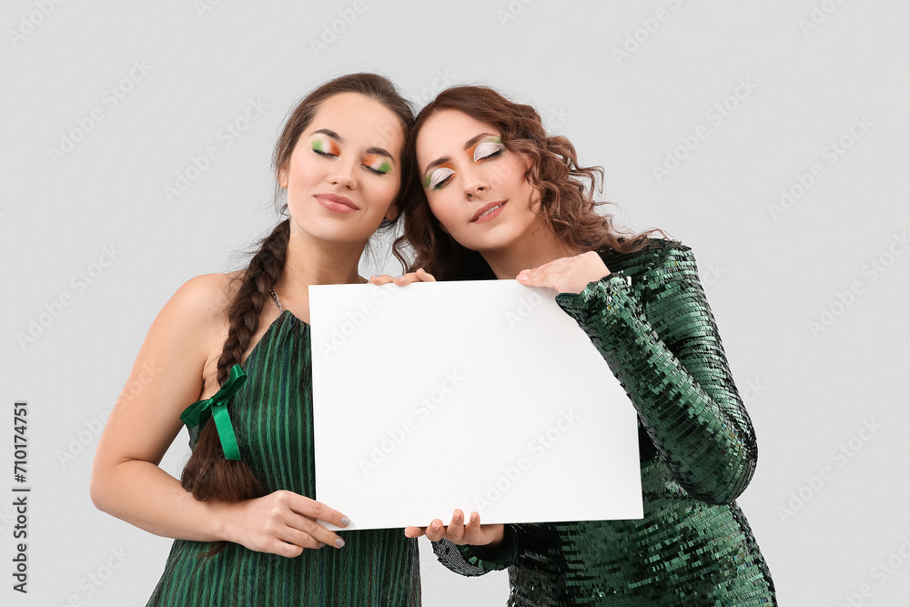 Women with blank poster on light background. St. Patrick's Day celebration Women with blank poster on light background. St. Patrick's Day celebration