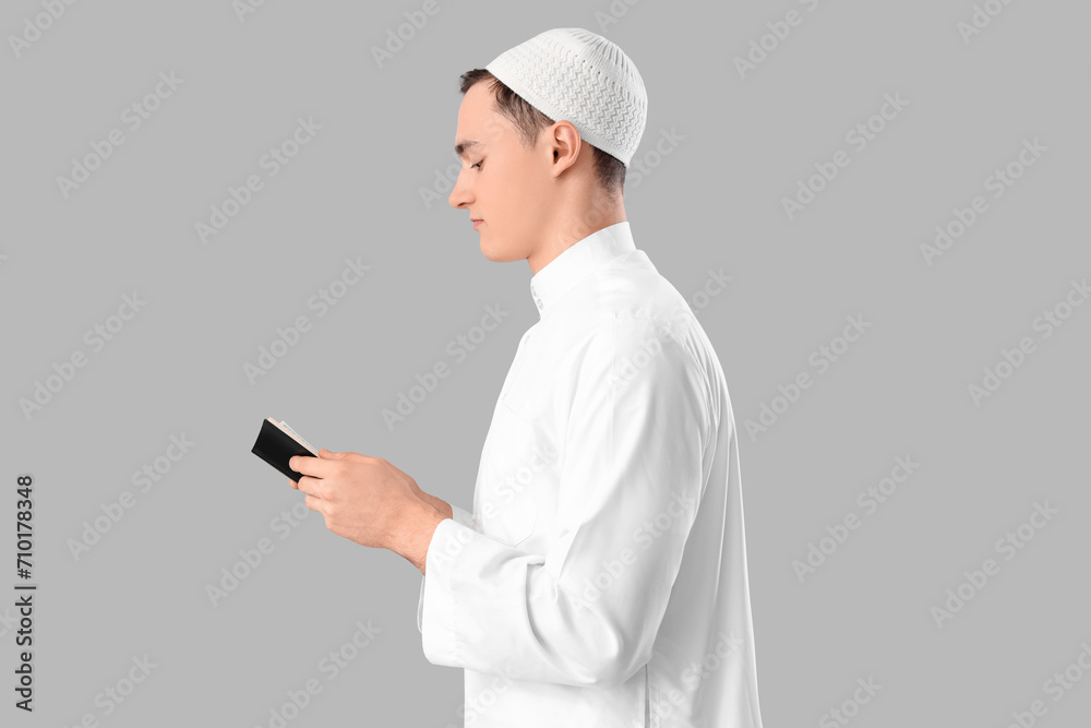 Young Muslim man with Koran on light background. Ramadan celebration