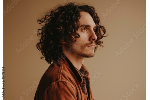 Stylish man with curly hair poses confidently.