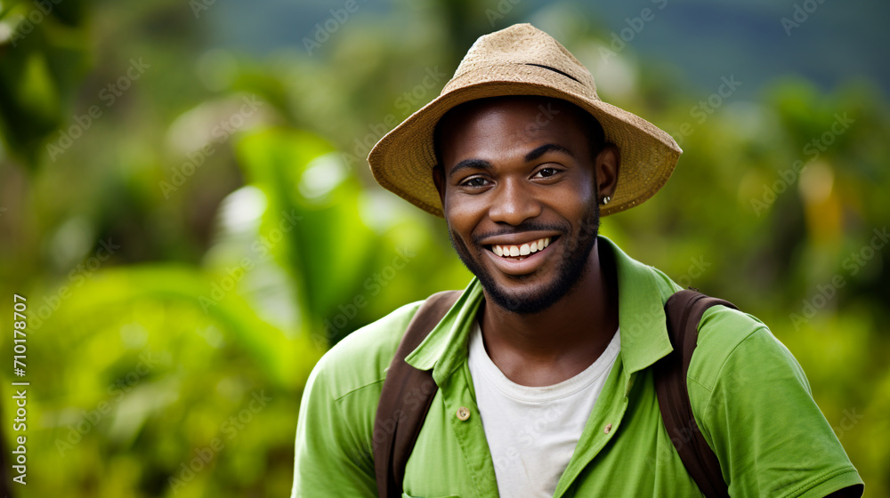 A smiling young African American man in a straw hat and green shirt enjoying nature