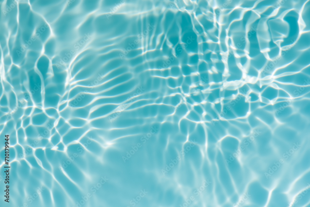 Bluewater waves on the surface ripples blurred. Defocus blurred transparent blue colored clear calm water surface texture with splash and bubbles. Water waves with shining pattern texture background.