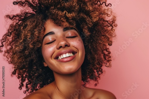 Young female model with curly hair laughing in profile photo for skin care, cosmetic, and spa product advertisement.