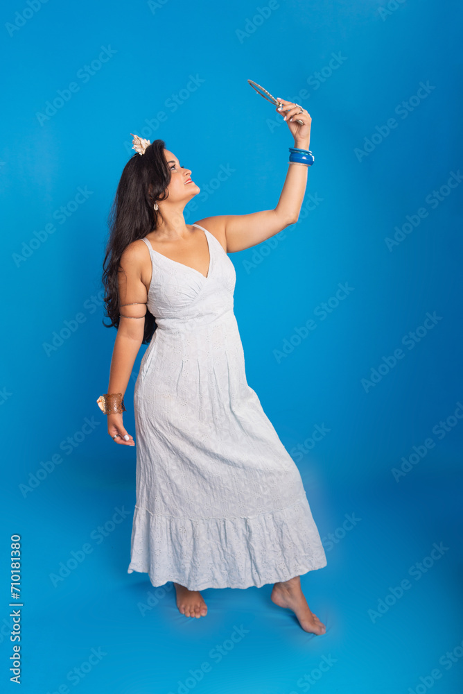 Portrait of beautiful black-haired woman wearing white clothing, holding and looking into a mirror. Portrait of beautiful black-haired woman wearing white clothing, holding and looking into a mirror.