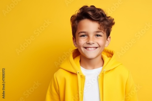Portrait of a smiling little boy in yellow hoodie over yellow background © Iigo