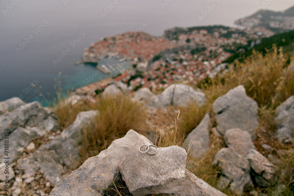 Wedding rings lie on a stone on a mountain above the sea