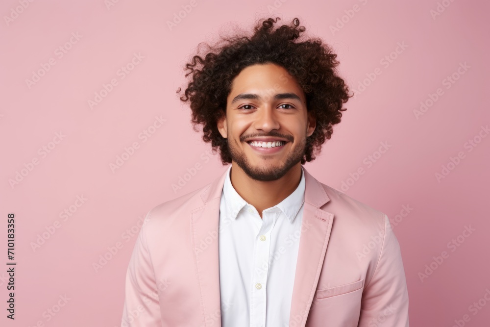 Portrait of young african american man with curly hair, dressed in pink suit, isolated over pink background