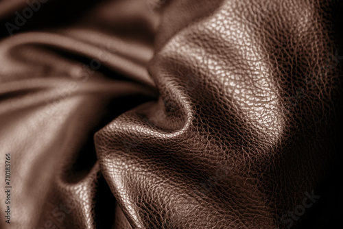 Brown leather with waves and folds. Textured background of faux or eco leather, vegan artificial material on PVC base. Close up of texture, macro