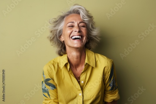Portrait of happy senior woman laughing and looking up against green background © Iigo