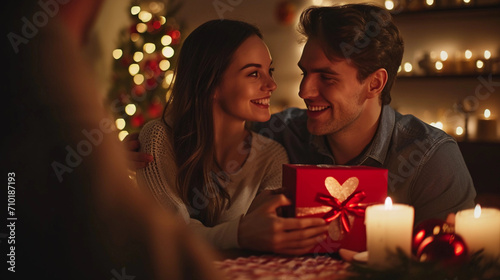 Husband or Boyfriend Holding Red Gift Box in Hands, Making Present Surprise to Happy Girlfriend Wife Having a Romantic Dinner Date in Candlelight, Close Up. Couple Celebrates Valentine's Day on Februa