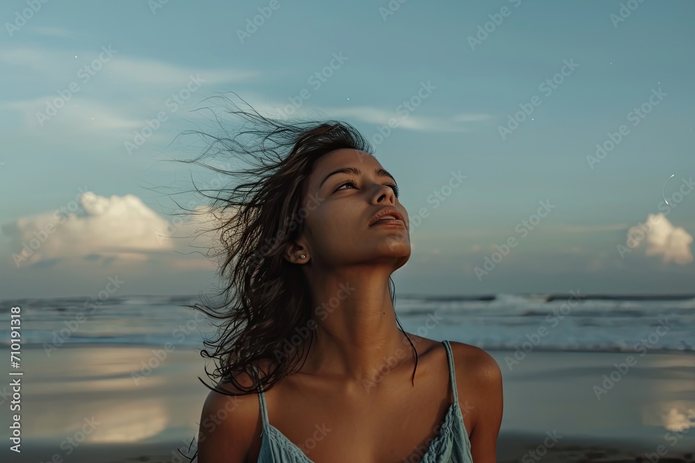 A lone woman gazes wistfully at the endless expanse of sky and ocean, embodying the freedom and serenity of a carefree summer day on the beach
