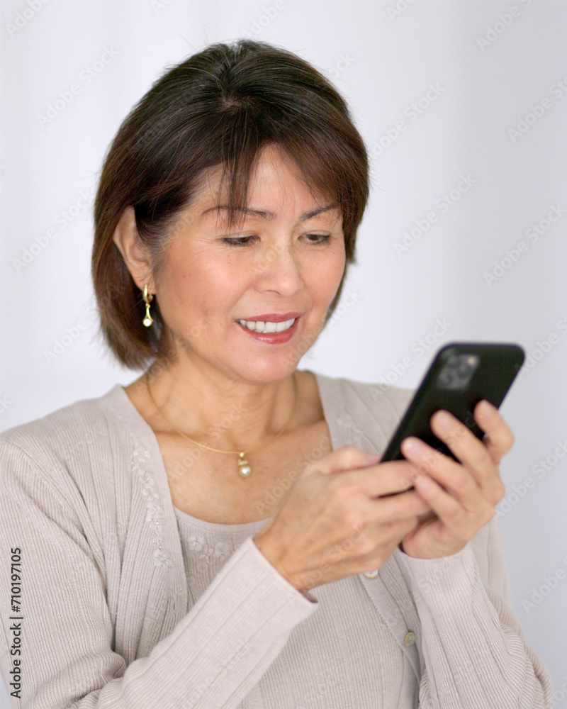 Smiling beautiful woman enjoying texting reading email on mobile phone relaxing standing bright background isolated.